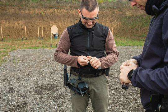 Two shooters are putting bullets into gun cartridges on a practical shooting training