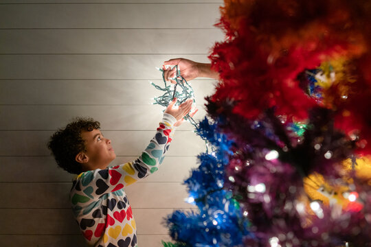 Girl takes string of Christmas lights from unseen person