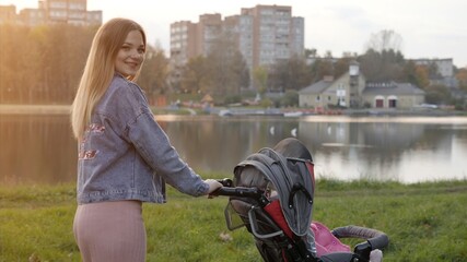 A young mother with a stroller walks in the autumn evening.