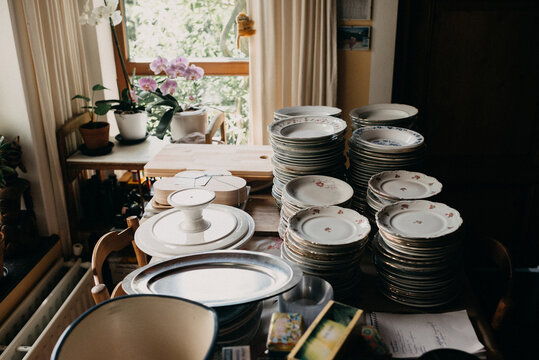 Antique porcelain plates stacked on a wooden table together with other kitchen utilites