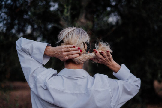 senior woman from back at field picking up her hair with flamenco attitude.