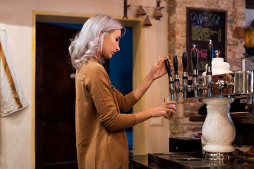 Woman bartender preparing a beer