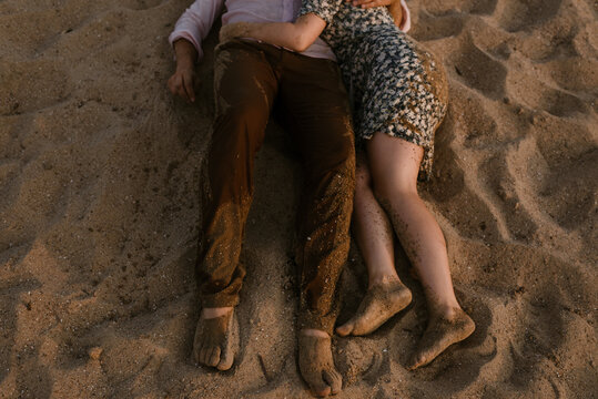 close up of young couples feet covered in sand on the beach