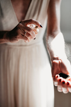 closeup of bride spraying perfume while sun hits her fragile skin