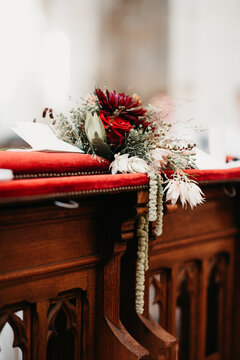 a beautiful wedding bouquet with white and red details laying down in church
