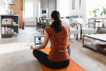 Brunette woman taking an online yoga class at home