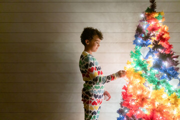 Girl in pajamas looks at rainbow tree