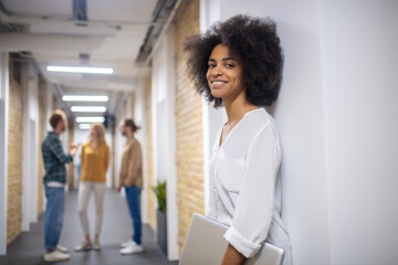 Curly-haired standing near the wall with a laptop in hands