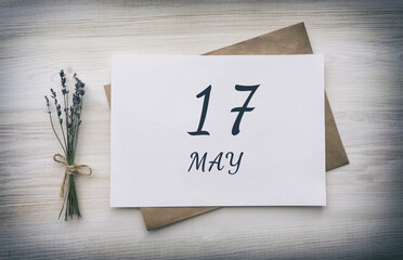 may 17. 17th day of the month, calendar date. White blank of paper with a brown envelope, dry bouquet of lavender flowers on a wooden background. Spring month, day of the year concept