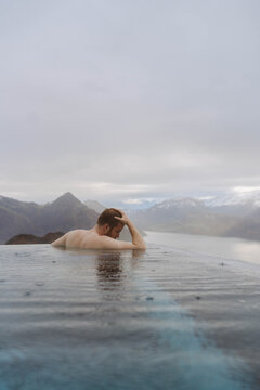 a young man in an outdoor swimming pool looking at the mountains