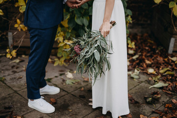 bride and groom holding hands in front of autumn colored garden