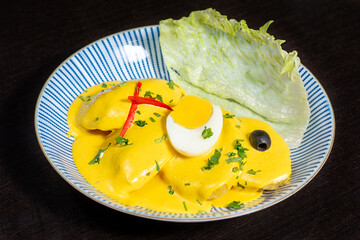 Peruvian traditional food. Potatoes with aji, yellow sauce, boiled eggs, decorated by olives and pepper. Papa a la huancaina