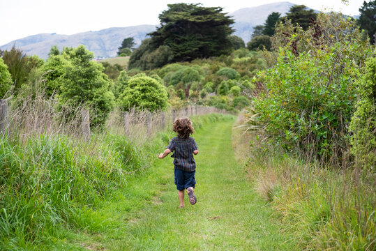 Boy running down a grassy road.