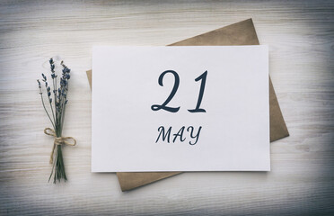 may 21. 21th day of the month, calendar date. White blank of paper with a brown envelope, dry bouquet of lavender flowers on a wooden background. Spring month, day of the year concept