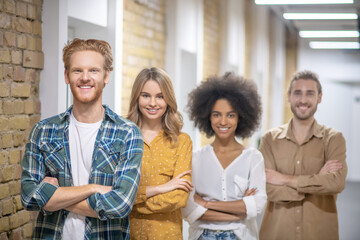 Group of young professionals standing with crossed arms and smiling
