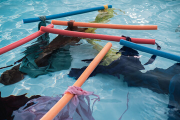 Several colors of sheets attached to pool floats are floating in a pool
