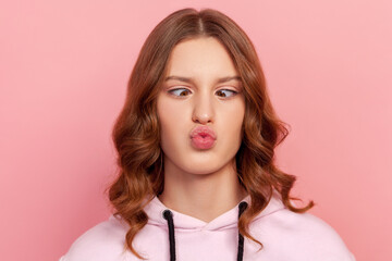Closeup portrait of funny teenager girl with curly hair making silly face with crossed eyes,...