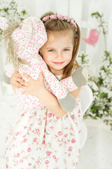 Portrait of little girl embrace pink horse with fresh white flowers background