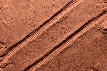 Tyre pattern on the reddish-orange sandy surface with copy space. Imitation of the traces of the rover on the planet Mars. Top view