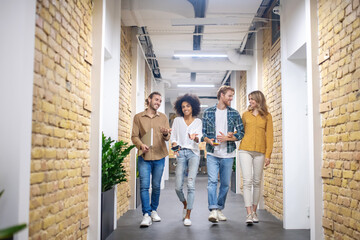 Group of smiling young people walking in the corridor