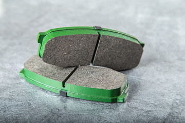 a set of new green brake pads on a gray table