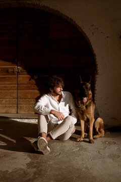 Fashionable man playing with his cute dog at home, in the countryside