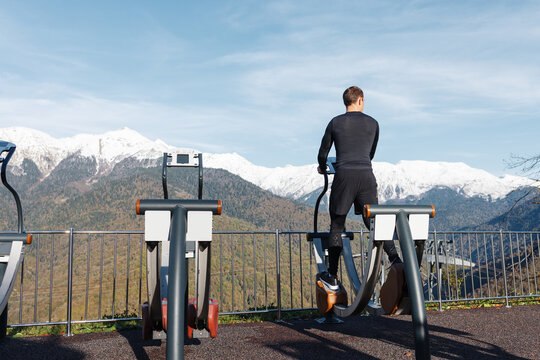 Unrecognizable sportsman exercising on walking machine in mountains
