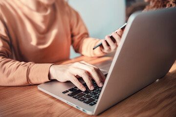 Woman using laptop and smart phone on desk in office place