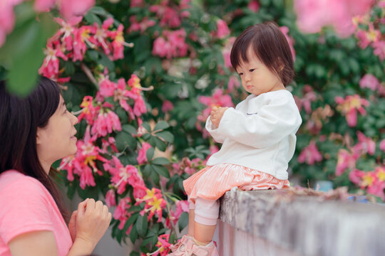 Little girl and mom outdoors with pink flower background