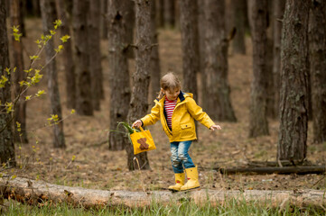 Adorable little girl hiking in forest. Kid in yellow coat and boots in beautiful nature. Sustainable renovation.