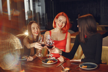 Friends talking and having fun at dinner party. Elegantly dressed women of people having a dinner.