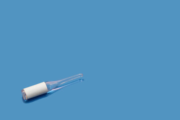 Glass ampoule with a liquid medicine on a blue background, there is a place to insert text.