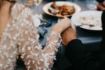 Wedding couple holding hands at dinner