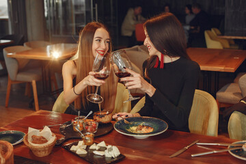 Friends talking and having fun at dinner party. Elegantly dressed women of people having a dinner.
