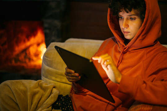 Woman with iPad near fire place.