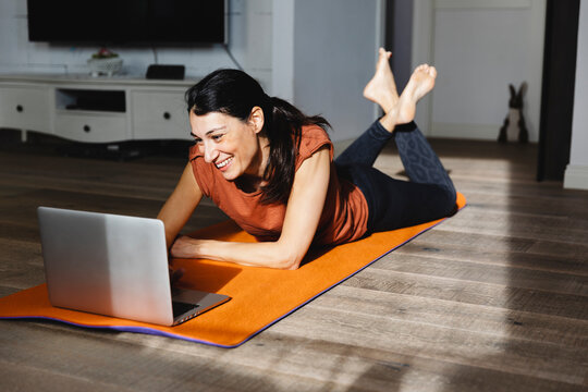 Smiling Woman On Yoga Mat Using Laptop At Home