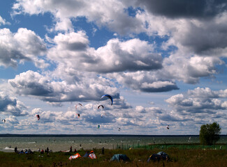 photo of a lake on a bright Sunny day with clouds and kitesurfers