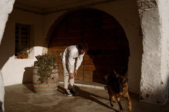 Fashionable man playing with his cute dog at home, in the countryside