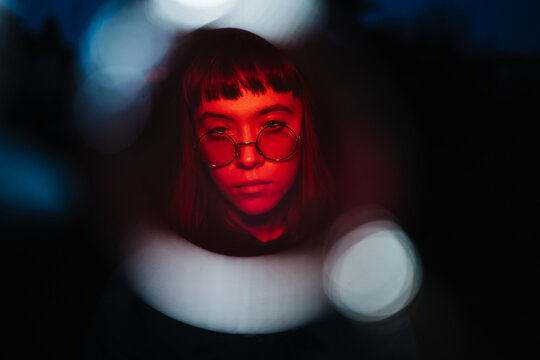 Young woman wearing sunglasses in red light