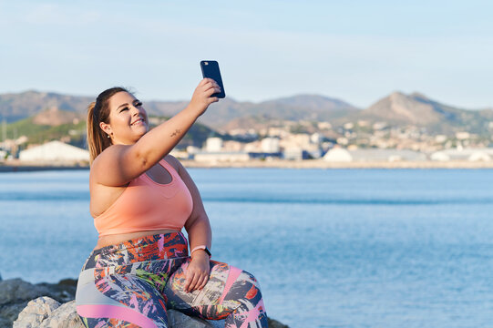 Full-figured woman taking selfies by the ocean