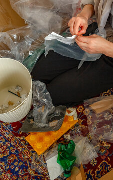 Unrecognizable female preparing packaging for recycling near bin
