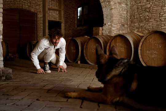 Young winemaker and his dog, inside his winery in the countryside