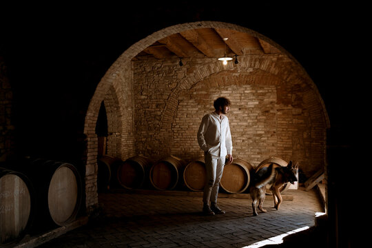 Young winemaker and his dog, inside his winery in the countryside