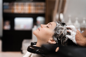 hairdresser washing hair to a client with shampoo