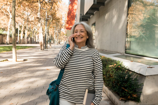mature woman walking on the streets while talking on the phone