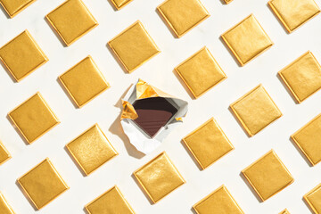Unwrapped chocolate amidst rows of golden pieces