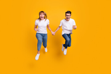 Full length photo of purposeful excited young couple wear white t-shirt jumping running fast...