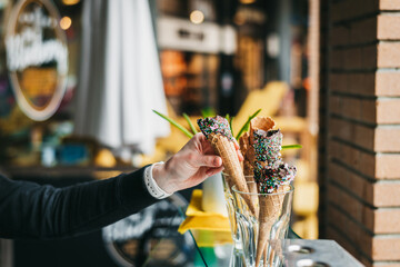 A womans hand is scooping homemade  ice cream onto handmade waffle ice cream cones