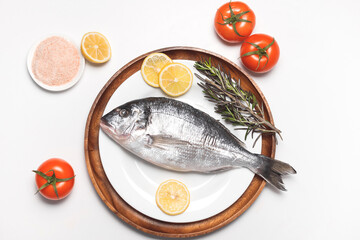 Dorado or spar fish or gilt-head bream served on white plate on white background, flat lay, top view