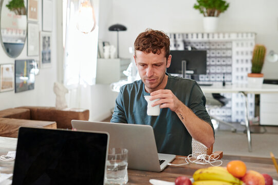 Designer drinking coffee while using a laptop